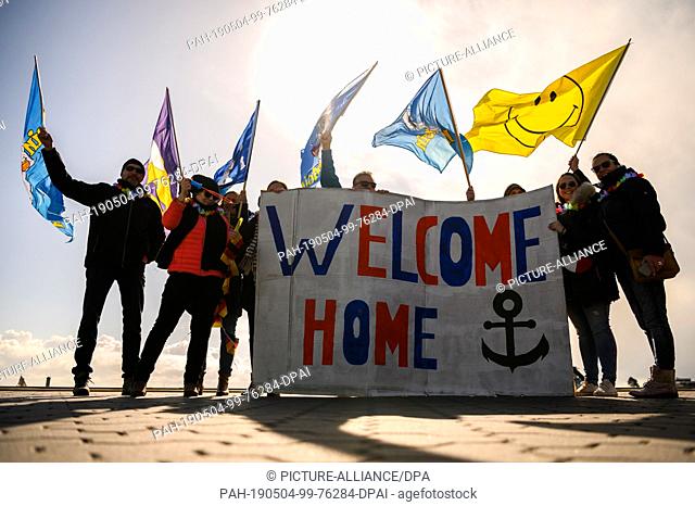 04 May 2019, Lower Saxony, Wilhelmshaven: A group of relatives is waiting with flags and a large cardboard sign with the inscription ""Welcome Home"" for the...