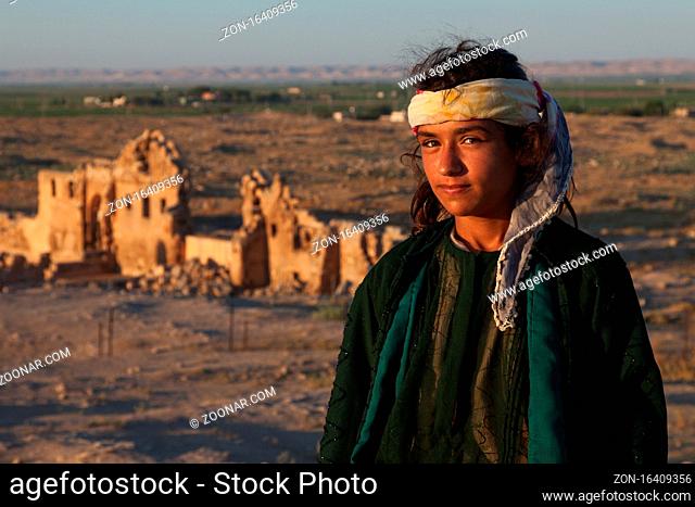 Sanliurfa, Turkey - July 21, 2010: Unidentified young girl standing in front of the ruins of ancient Harran University and Ulu Mosque ( Ulu Cami ) with her...