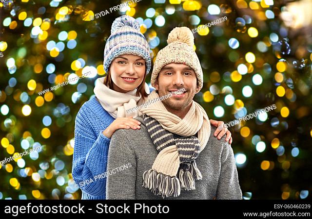 happy couple in winter clothes christmas lights