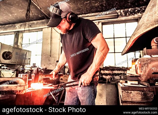 Knife maker working with damask steel at hydraulic sledge-hammer