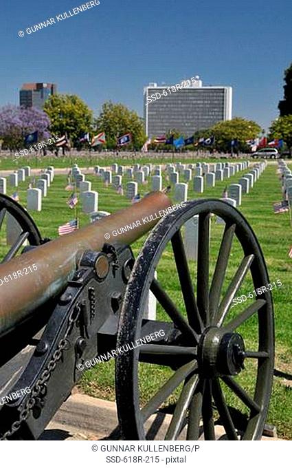 Cannon in a cemetery with a government building in the background, Westwood Federal, Los Angeles National Cemetery, Los Angeles, California, USA