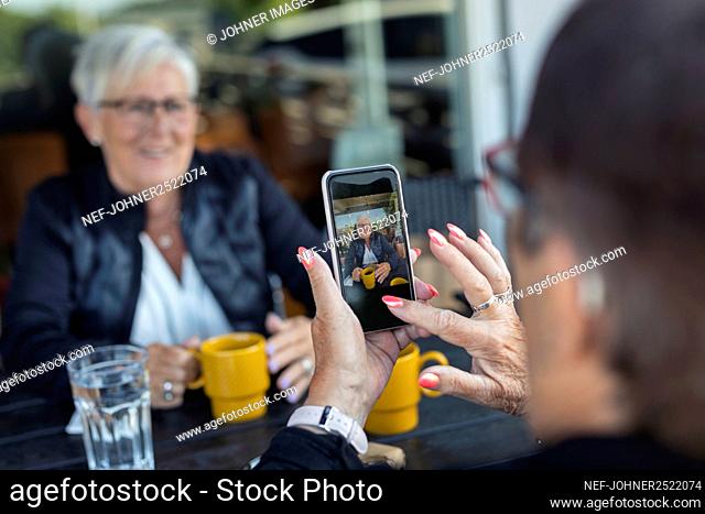 Woman taking photo of her friend in cafe