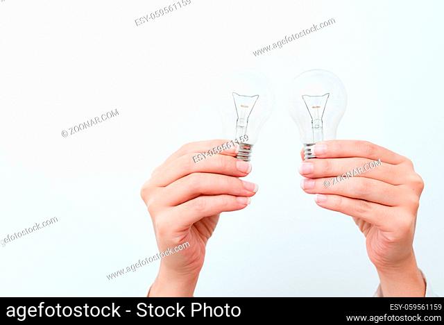 Woman Hands Holding Lamp Presenting Ideas For Project, Man Palm Showing Bulbs And New Technologies, Two Held Lightbulbs Exhibiting Another Opinion