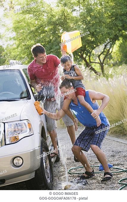 Gay couple washing the car with their son