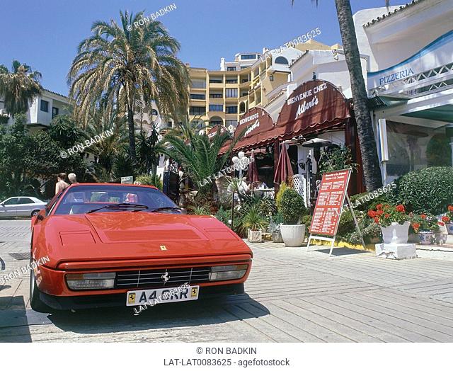 Puerto Cabopino. Red Ferrari sportscar. On quay. Restaurant/ buildings