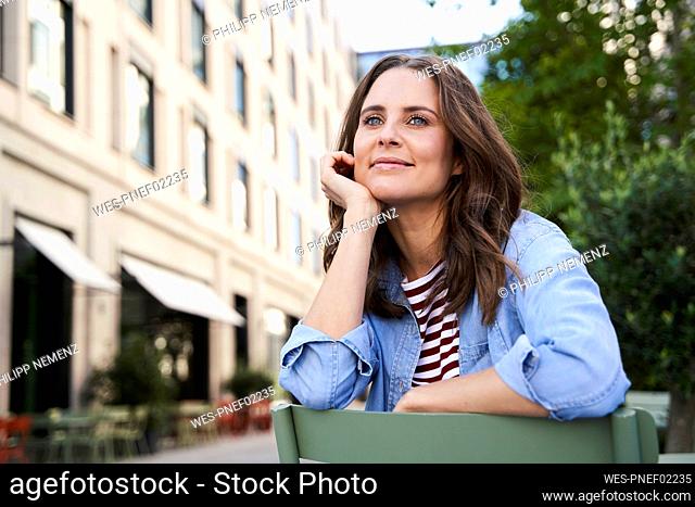 Portrait of smiling brunette woman sitting on a chair in the city