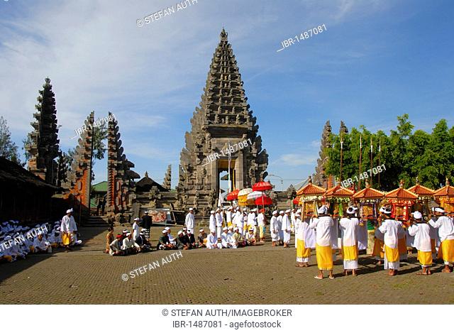 Balinese Hinduism, gathering of believers, ceremony, believers in bright temple dress carrying colourful parasols and shrines