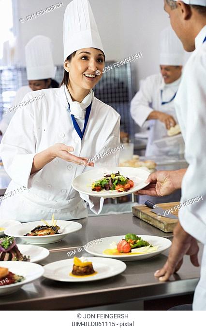 Asian female chef handing plate of food