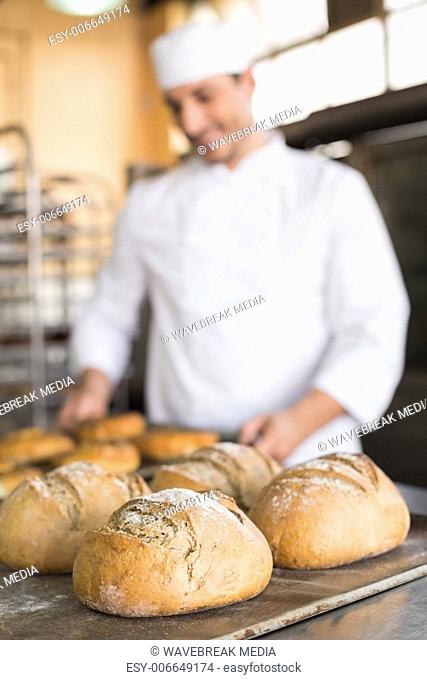 Happy baker taking out fresh bagels