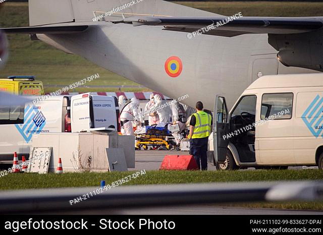 02 November 2021, Hamburg: Medical personnel in protective suits push a Corona intensive care patient on a hospital bed out of the hold of a Romanian Air Force...
