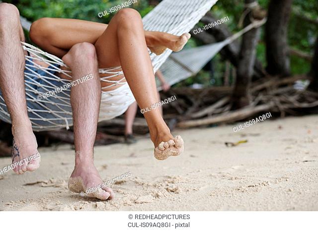 Young couples legs on beach hammock, Kradan, Thailand