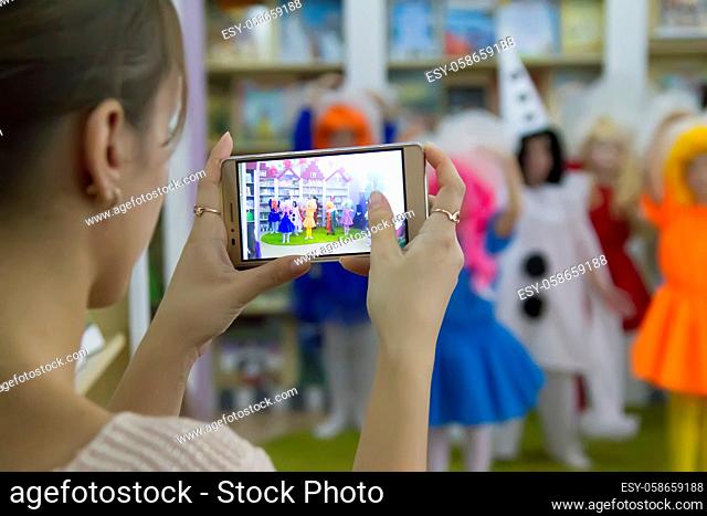 Belarus, the city of Gomel, October 30, 2017. Opening of the children's library department.A woman is taking pictures of children on a mobile phone