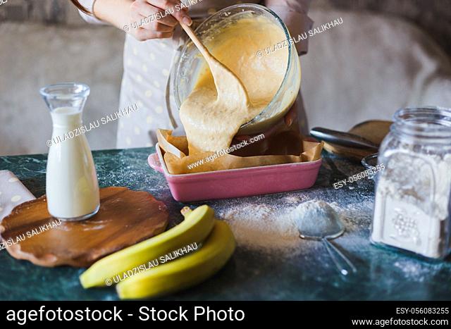 Woman is pouring dough into a baking tray