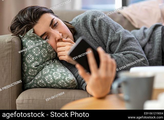 stressed woman with smartphone on sofa at home