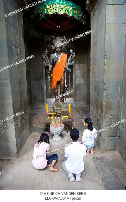 Asian Trio Praying to Buddah Statue  Angkor Wat Temple Complex, Siem Riep, Cambodia