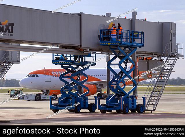 22 October 2020, Brandenburg, Schönefeld: Two employees attach the ""Sixt"" lettering to a passenger boarding bridge during a press meeting on the subject of...
