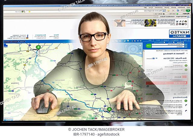 Young woman sitting at a computer surfing the Internet, viewing a page with a route planner for a journey with traffic information