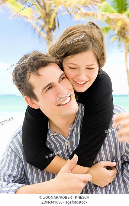 Junge Frau umarmt ihren Partner am tropischen Strand von hinten Model r.: Marlene