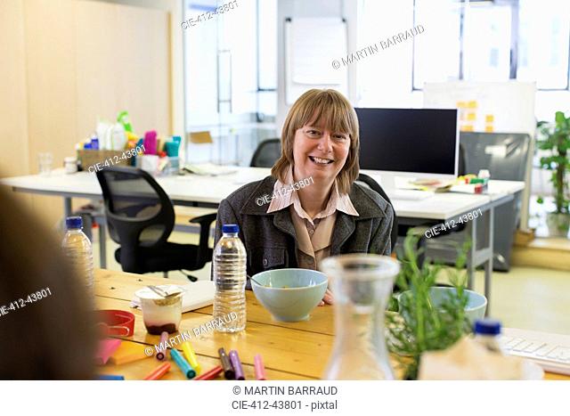 Portrait smiling, confident businesswoman eating in office