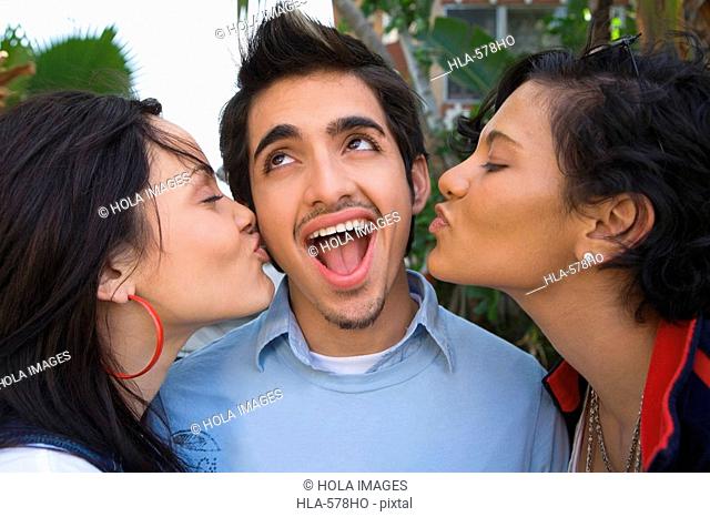 Close-up of two young women kissing a young man