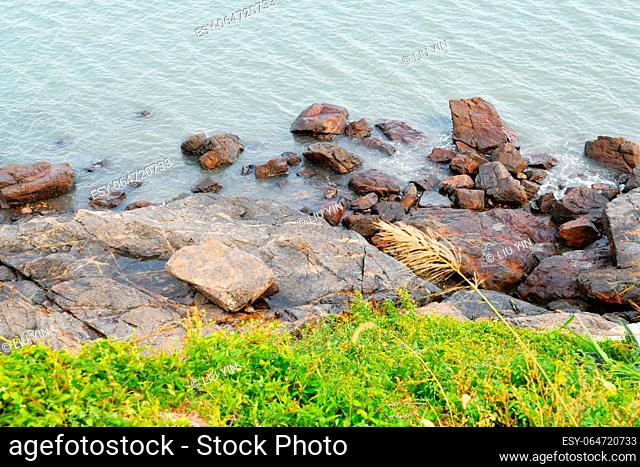 Photo of some weathered eroded cracked rocks on the coastline