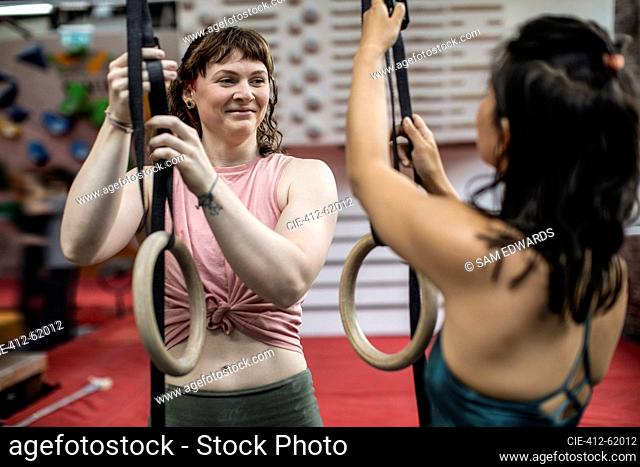 Smiling young women exercising at gymnastics rings