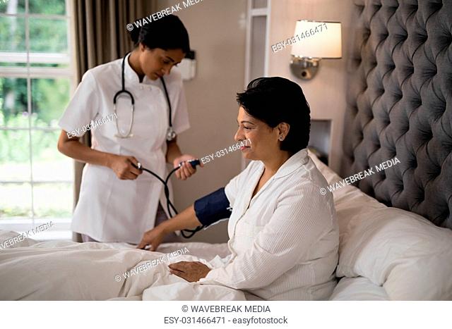 Nurse checking blood pressure of patient resting on bed