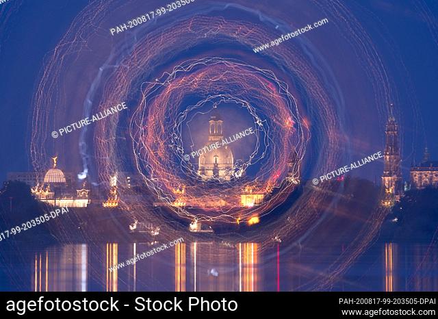 17 August 2020, Saxony, Dresden: Brightly illuminated is the backdrop of Dresden's old town in front of the Elbe river at nightfall (long exposure and turning...