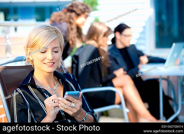 Young businesswoman using smart mobile phone, outside office building