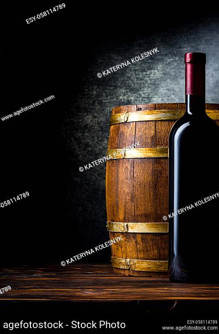 Bottle of red wine and wooden barrel on a black background