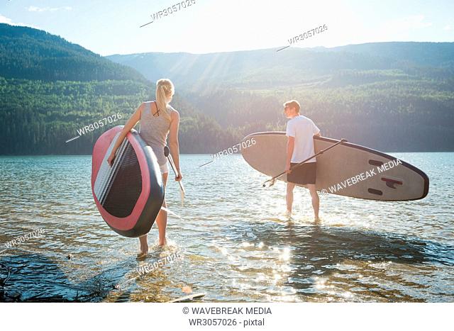 Couple with stand up paddleboard walking in river