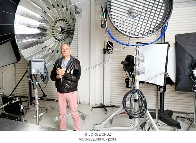 Senior photographer with camera and light reflectors in studio