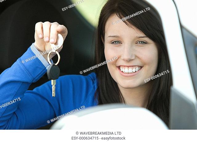 Brunette teen girl sitting in her car holding keys after bying a new car