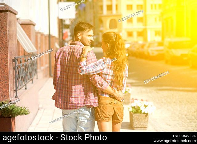 Young couple hugging in the city centre. Beautiful couple walking on the pavement of European country. Toned image