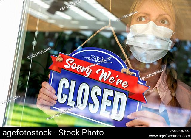 Female Store Owner Wearing Medical Face Mask Turning Sign to Closed in Window