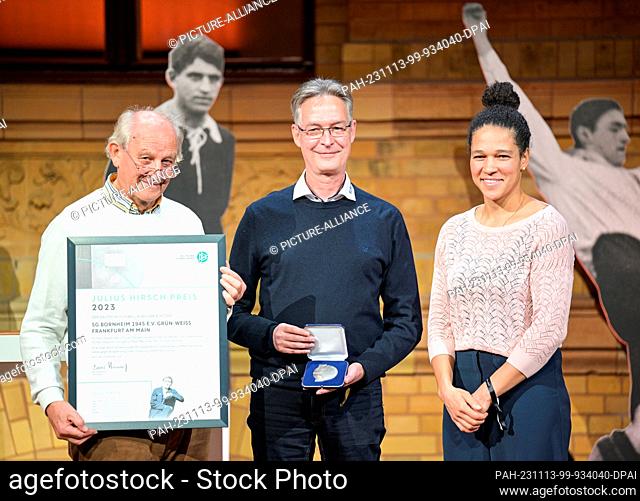 13 November 2023, Berlin: Harald Seehausen (l-r) and Jürgen Holzapfel from SG Bornheim Grün-Weiß receive the prize from Celia Sasic