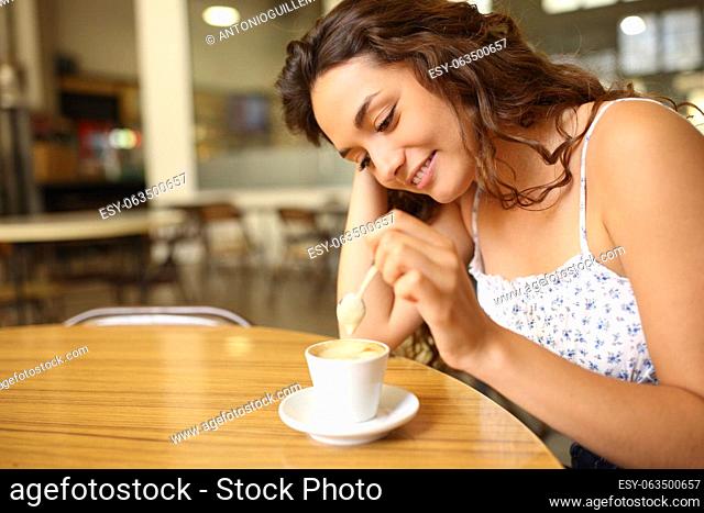 Candid woman stirring coffee sitting in a restaurant