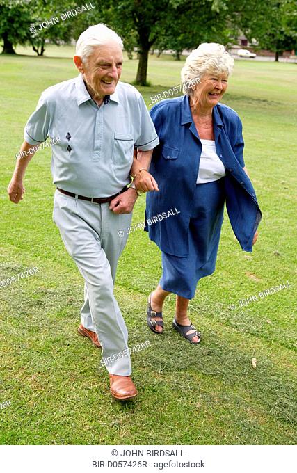 Older couple walking briskly in the park