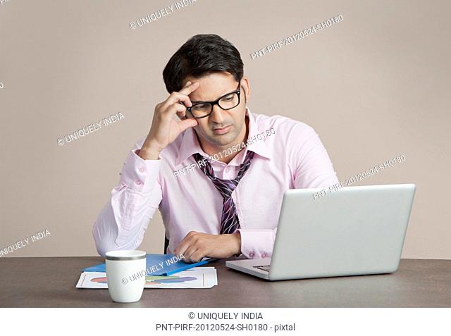 Businessman looking at a laptop and thinking
