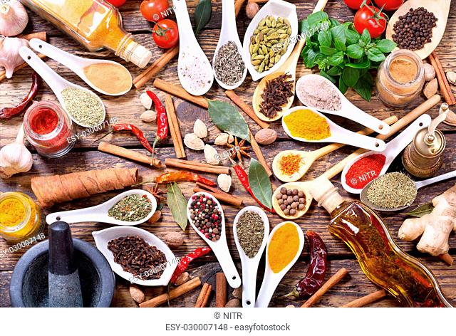 various herbs, spices and vegetables for cooking on wooden table, top view