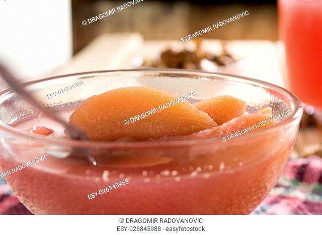 Apple compote with dried fruits in the cup on wooden table with decorative wallnuts
