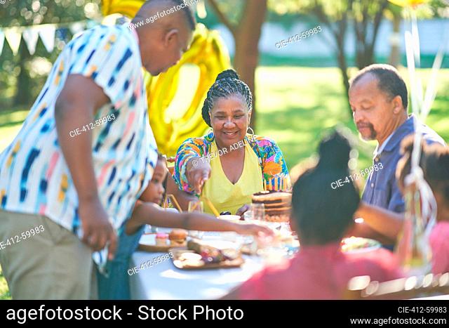 Multigenerational family celebrating birthday at summer patio table