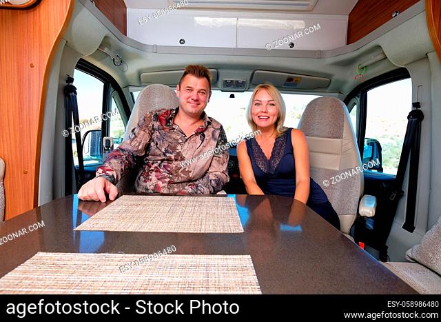 Married middle age couple sitting inside of recreational vehicle looking at camera. Active people lifestyle, adventure and journey