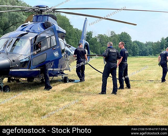 19 June 2021, Brandenburg, Oberkrämer: Police officers stand by a helicopter. In the largest forest fire so far since the beginning of the season