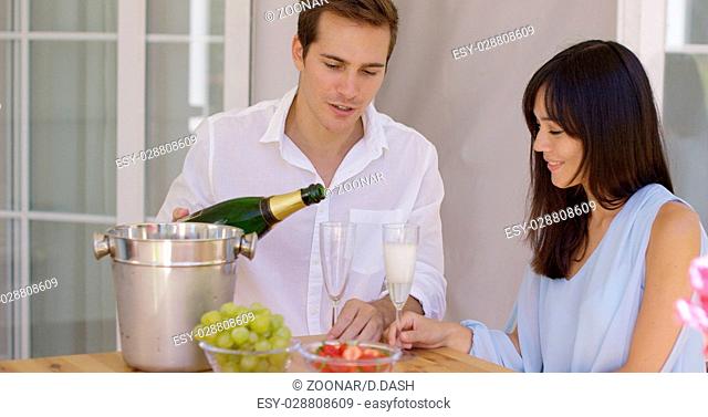 Smiling young couple pouring champagne to drink
