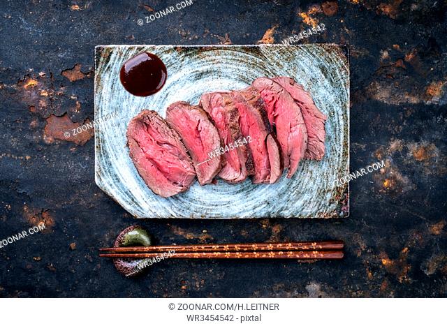 Japanese barbecue wagyu aged fillet steak slices as top view on a plate with copy space