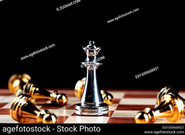 Silver queen chess defeats gold pawns on wooden chessboard. Intellectual duel and tactical battle in business. Strategy planning, leadership and teamwork