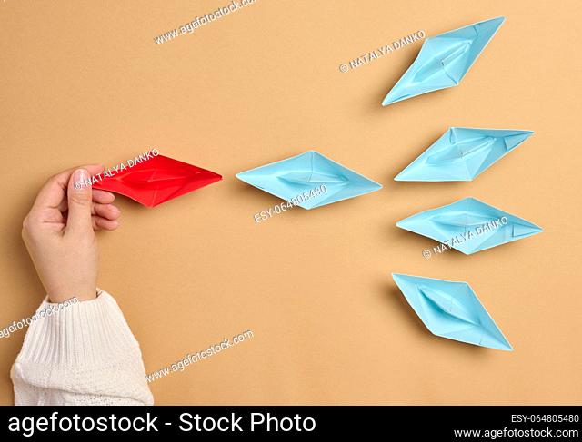 Group of paper boats on a brown background. Concept of a strong leader in a team, manipulation of the masses, following new perspectives