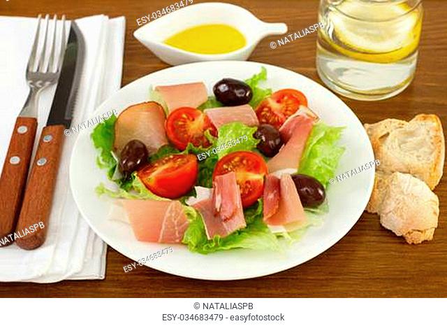 salad with prosciutto, olives, lettuce on the plate