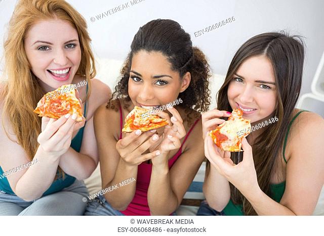 Portrait of happy female friends eating pizza at home